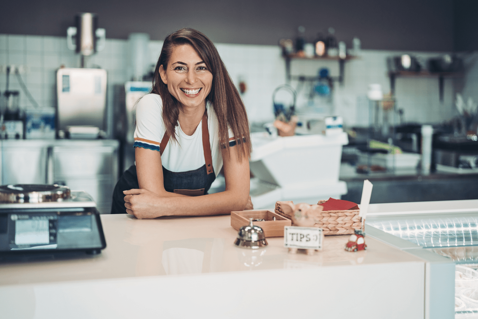 A smiling shop owner leaning on the counter in a cozy retail environment.