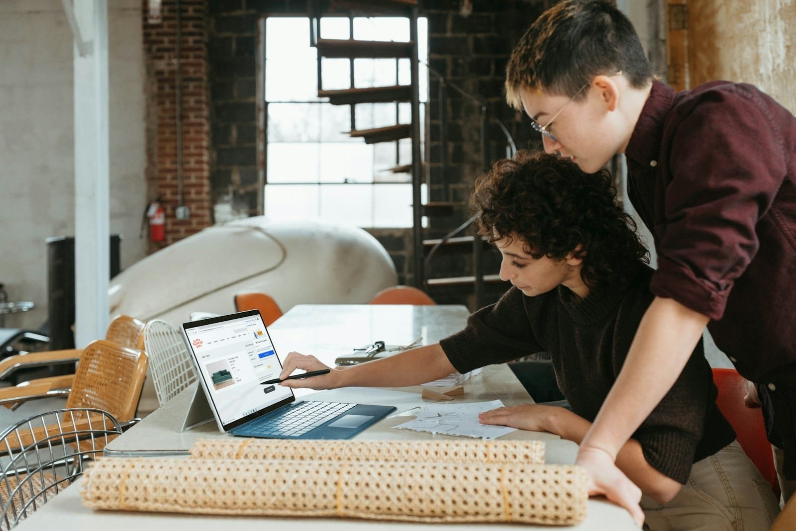 Two professionals collaborating on a laptop in a creative workspace, representing Happy Pixel Designs’ personalized approach to custom web and branding solutions for small businesses.