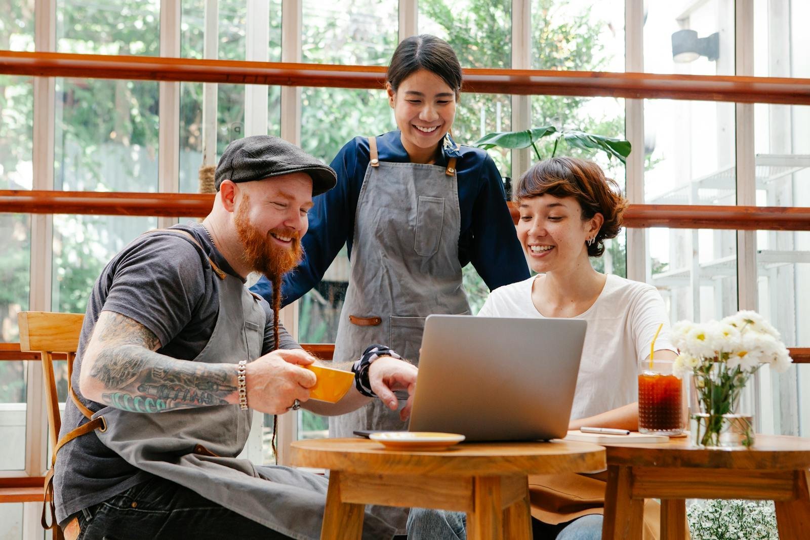 A cheerful restaurant team reviewing their website design on a laptop, symbolizing Happy Pixel Designs’ client-centered approach to web development.